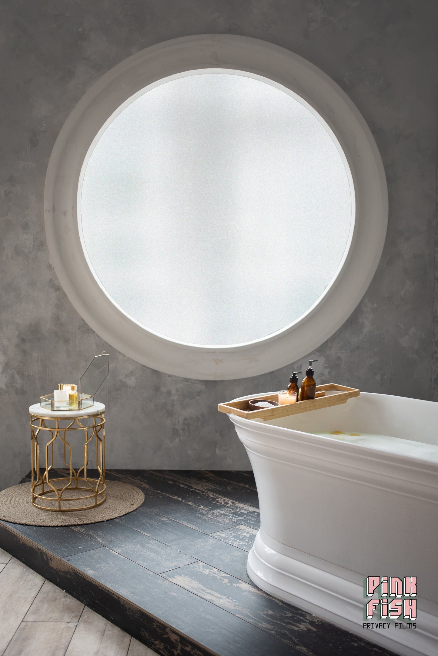 Modern bathroom with a large round window with frosted window film, freestanding bathtub, and small table.