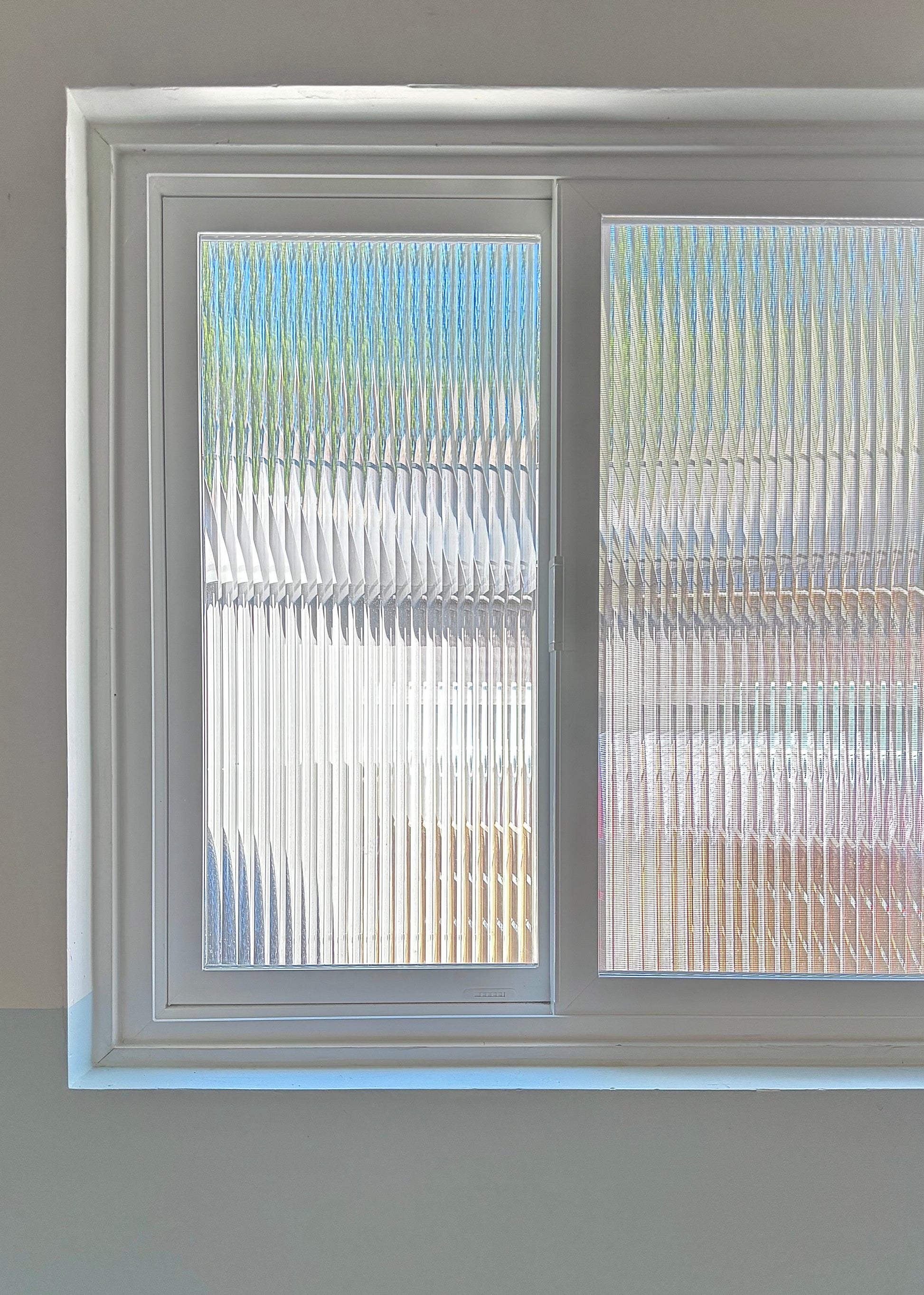 Window with reeded window film, showing a blurred outdoor scene.