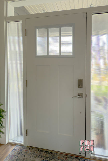 White door with fluted glass panels in a room with a patterned rug and plant.