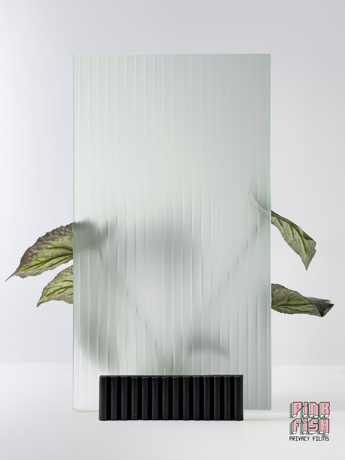 Decorative glass panel with a frosted ribbed textured pattern and black base, featuring a plant on a white background.