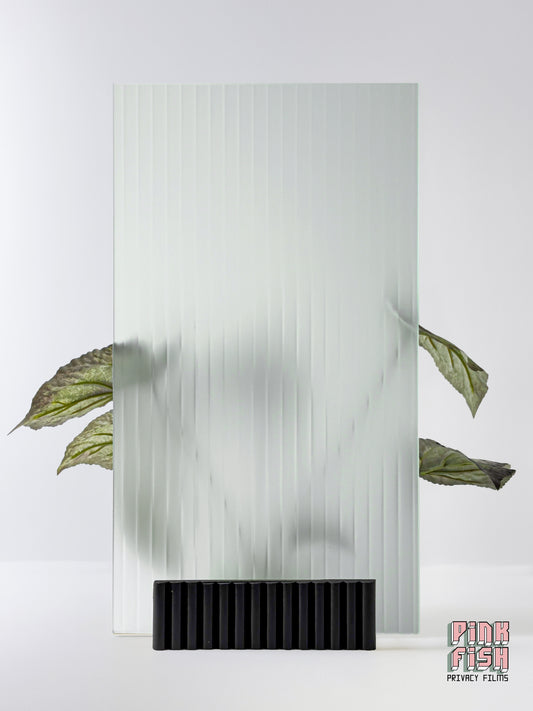 Decorative glass panel with a frosted ribbed textured pattern and black base, featuring a plant on a white background.